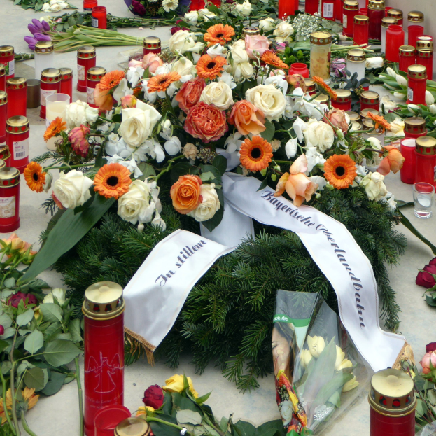 Gedenken in Berlin mit Blumen und Kerzen vor einer Wand.