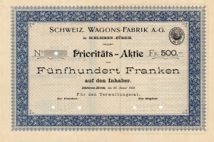 Ein altes deutsches Aktienzertifikat mit blauer Umrandung und der Aufschrift "Schweiz Wagons-Fabrik A.G." drauf.