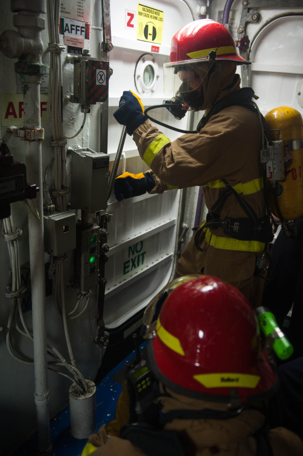 Zwei Feuerwehrleute in Schutzausrüstung inspizieren Equipment zwischen industriellen Rohren.