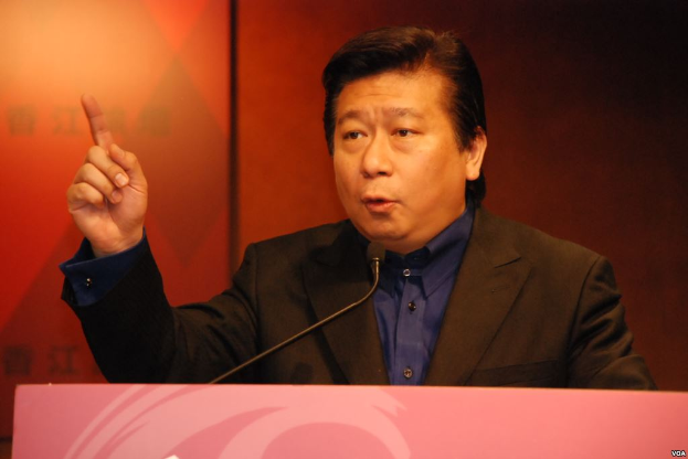 Ein Mann im Anzug und Krawatte hält eine Rede an einem Rednerpult mit Mikrofon und sieht ernst aus.