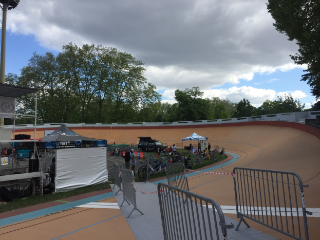 Gruppe von Radfahrern auf einer Schmutz-BMX-Strecke mit Geländern, Zelten, Fahrzeugen und Bäumen im Hintergrund während der UCI-BMX-Weltmeisterschaften 2018.