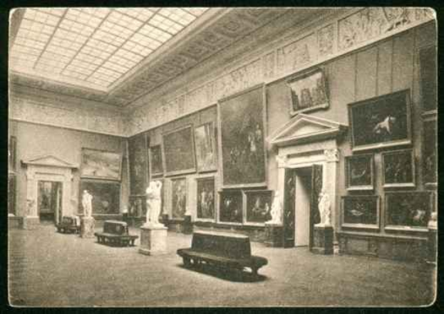 Ein altes Schwarz-Weiß-Foto eines großen Raums in der National Gallery of Art in London, der Skulpturen, Bänke, Fotorahmen an den Wänden und eine Decke mit einem Dachlicht zeigt.