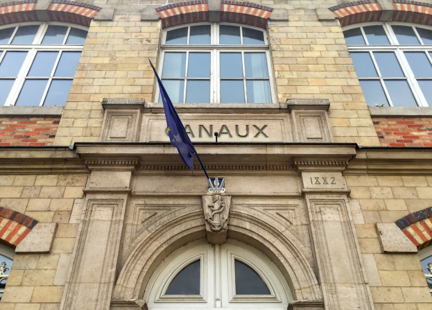 Ein Gebäude mit Glasfenstern und einer Tür, eine Flagge davor und ein Text, der darauf hinweist, dass es ein Hotel ist.
