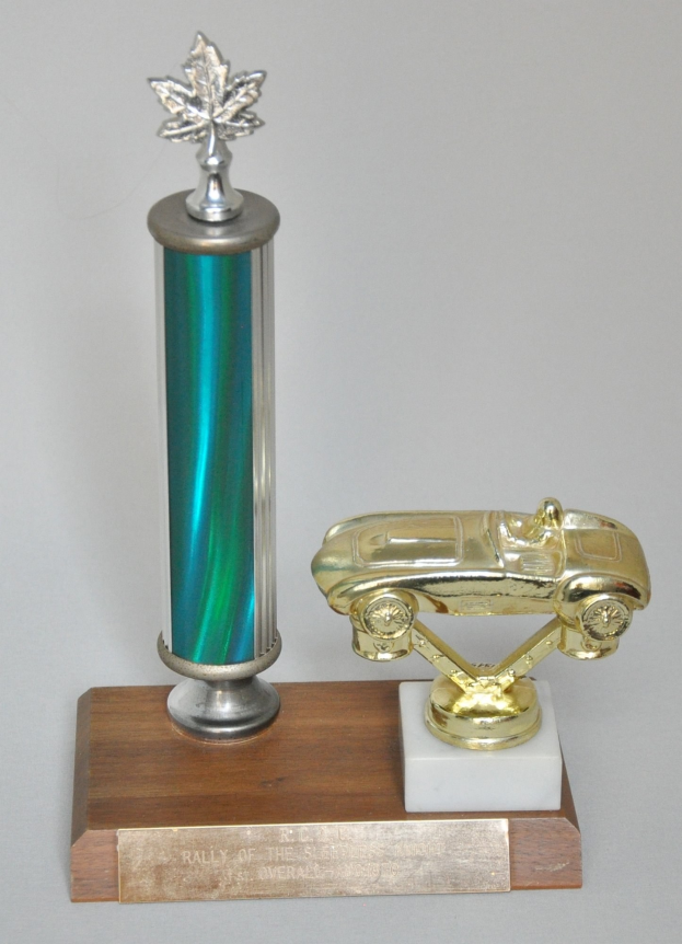 Ein Pokal mit einem glänzenden, detailreichen Modellauto auf einer hellen Holzplatte.