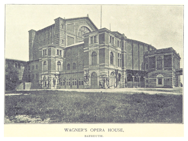 Schwarzes und weißes Foto von Wagners Opernhaus in Bayreuth mit einigen Menschen vor dem Gebäude, umgeben von Bäumen und einem klaren Himmel, mit Text unten.