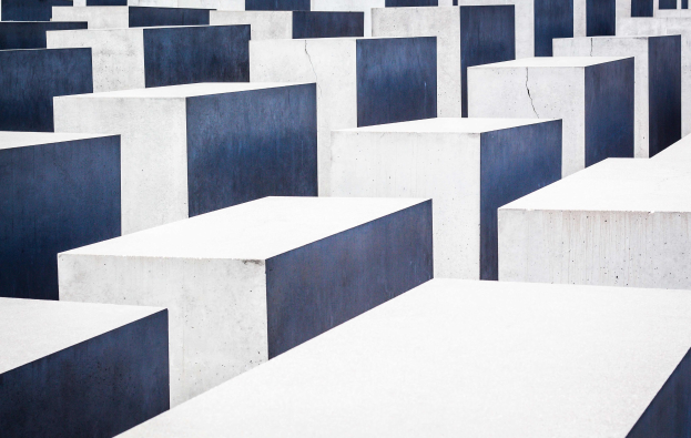 Luftaufnahme des Holocaust-Mahnmals für die ermordeten Juden Europas in Berlin, die ein Gitter aus grauen Betonsteinen in verschiedenen Höhen zeigt.