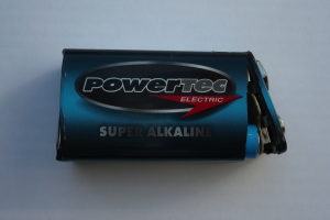 Eine blaue Powertec Super-Alkaline-Batterie auf einer weißen Oberfläche, beschriftet mit dem Wort "Powertec" in fetter Schrift.
