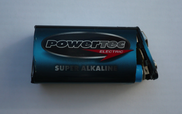 Eine blaue Powertec Super-Alkaline-Batterie auf einer weißen Oberfläche, beschriftet mit dem Wort "Powertec" in fetter Schrift.