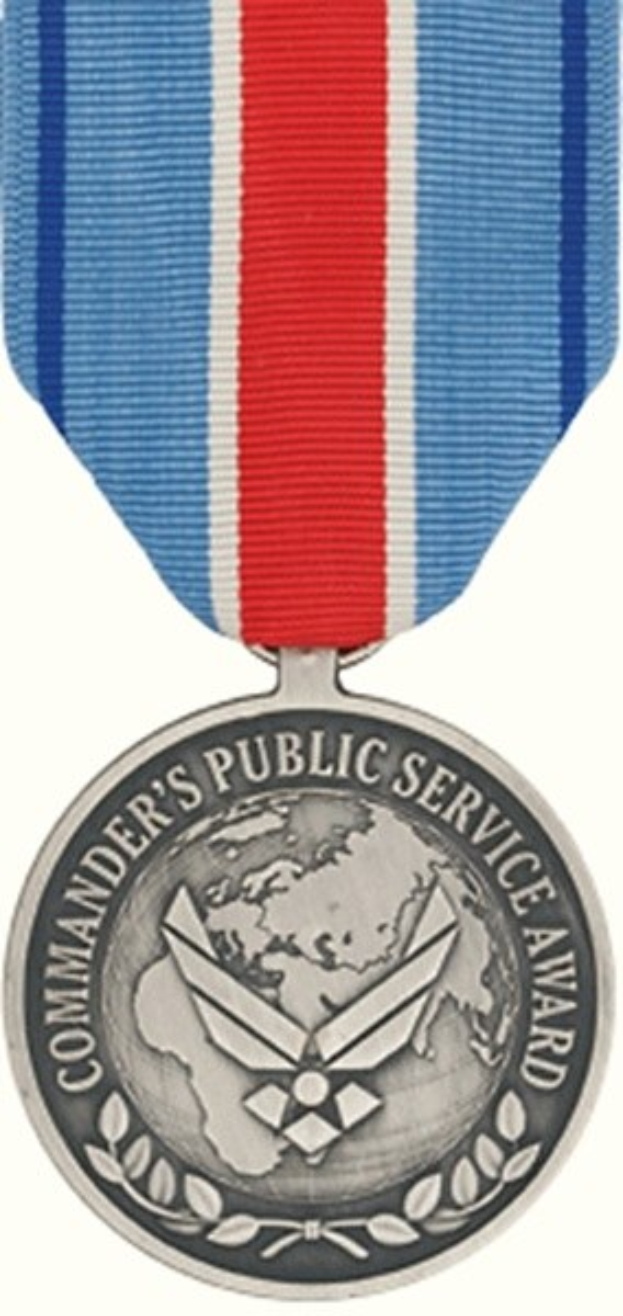 Silberne Medaille mit rot-weiß-blauem Band, beschriftet mit 'Commander's Public Service Award' vor weissem Hintergrund.