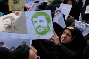 Eine Gruppe iranischer Frauen in schwarzer Kleidung, einige mit Brille, hält Fotos von Präsident Mahmoud Ahmadinejad während einer Demonstration in Tehran hoch.