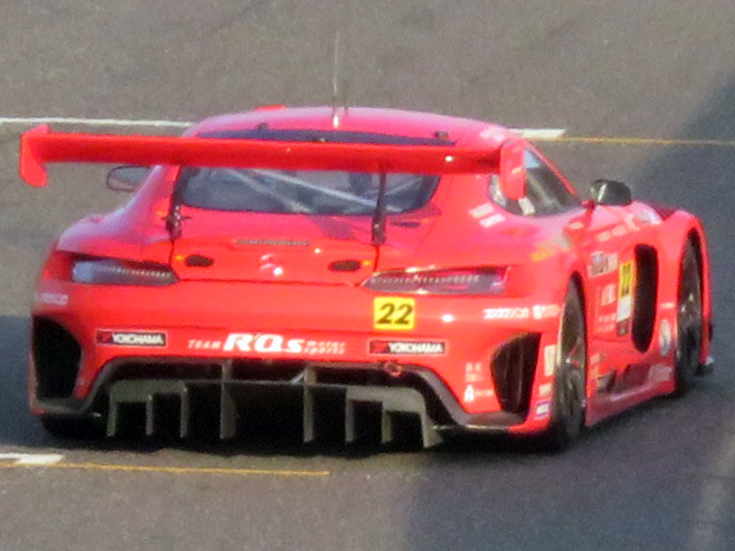Roter Porsche 911 GTS Rennauto mit großer Heckflosse und Spoiler, der auf einer Rennstrecke fährt.