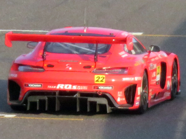 Roter Porsche 911 GTS Rennauto mit großer Heckflosse und Spoiler, der auf einer Rennstrecke fährt.