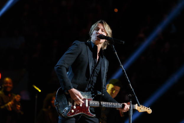 Keith Urban performs auf der Bühne im Joint im Hard Rock Hotel & Casino in Las Vegas, spielt Gitarre mit einem Mikrofon vor sich und Bandmitgliedern im Hintergrund bei gedämpftem Licht.