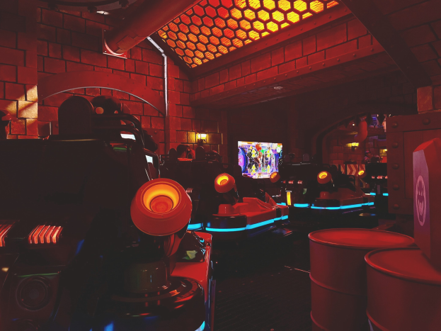 Ein hell erleuchteter Raum voller verschiedener Arcade-Videospielautomaten, Bildschirme und Geräte, der eine lebendige Atmosphäre schafft.