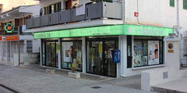 Eine Straßenansicht einer Apotheke mit umliegenden Gebäuden, Fahrzeugen und einem klaren Himmel.