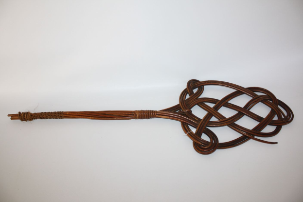 Eine braune Lederpeitsche mit einem Knoten, vor einem weißen Hintergrund.